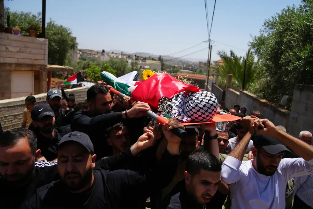 Mourners carry the body of Palestinian Zakaria Qatousa, during his...