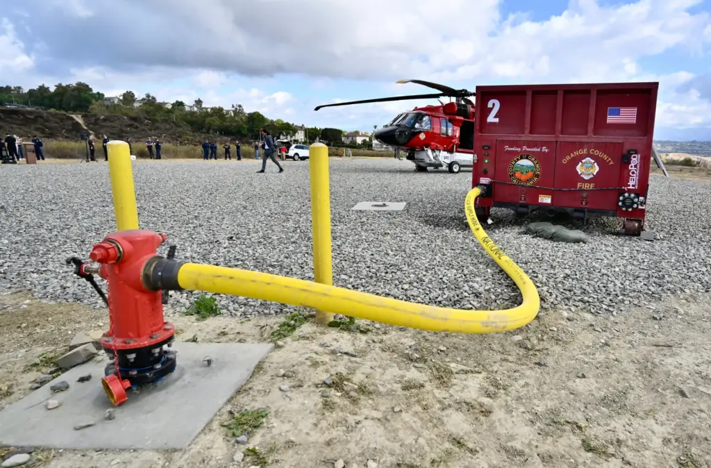 An OCFA helicopter demonstrates a water drop after sucking up...
