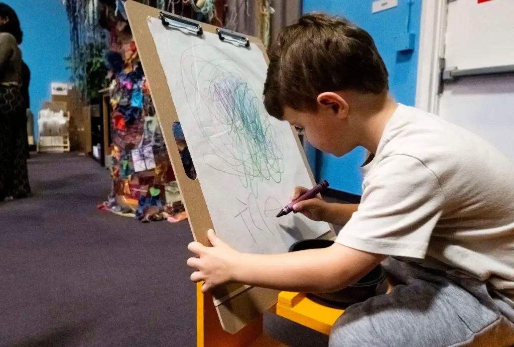 Tyler Wooldridge, 4, signs his name to the artwork he...