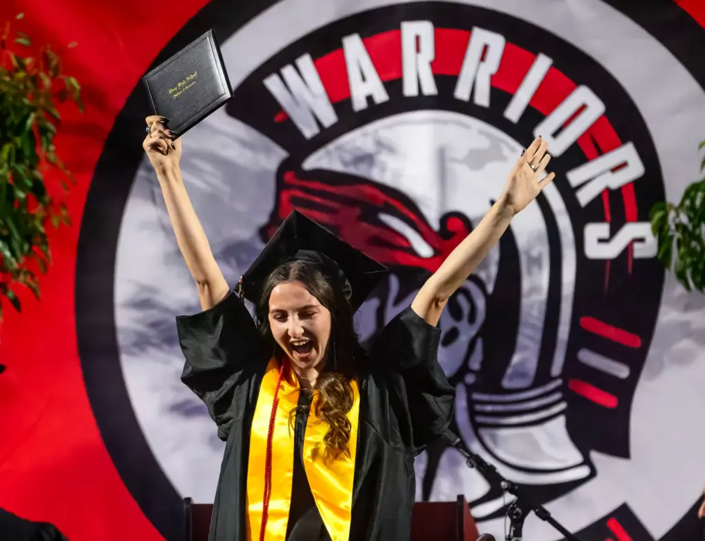 A graduate celebrates her accomplishment after receiving her diploma at...