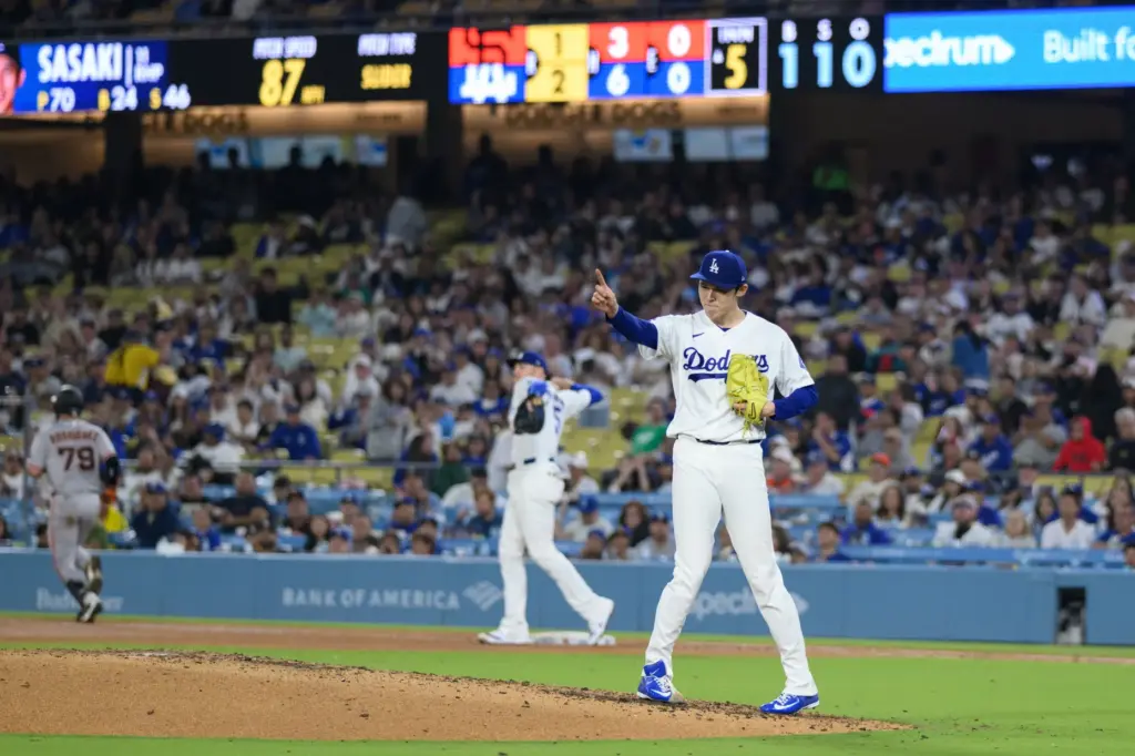 Dodgers starting pitcher Roki Sasaki gestures toward third baseman Max...