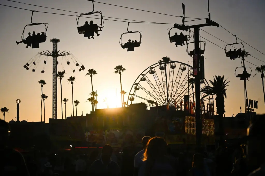 Fairgoers enjoy the evening as the sun sets during the...