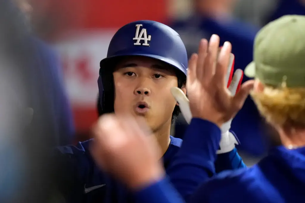 Dodgers’ Shohei Ohtani is congratulated by teammates in the dugout...