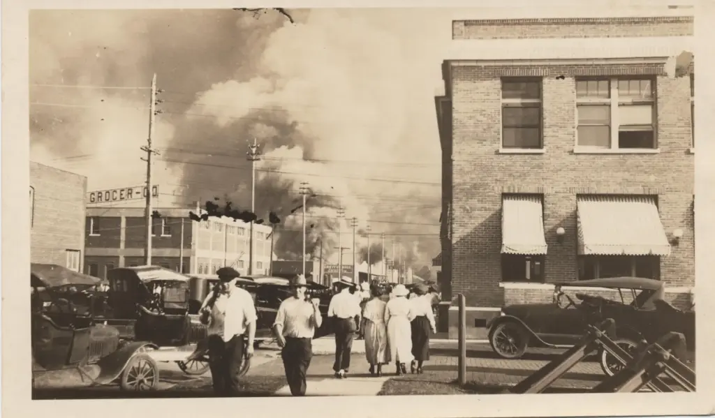 two armed men walking away from a billowing cloud of smoke during the Tulsa Race Massacre