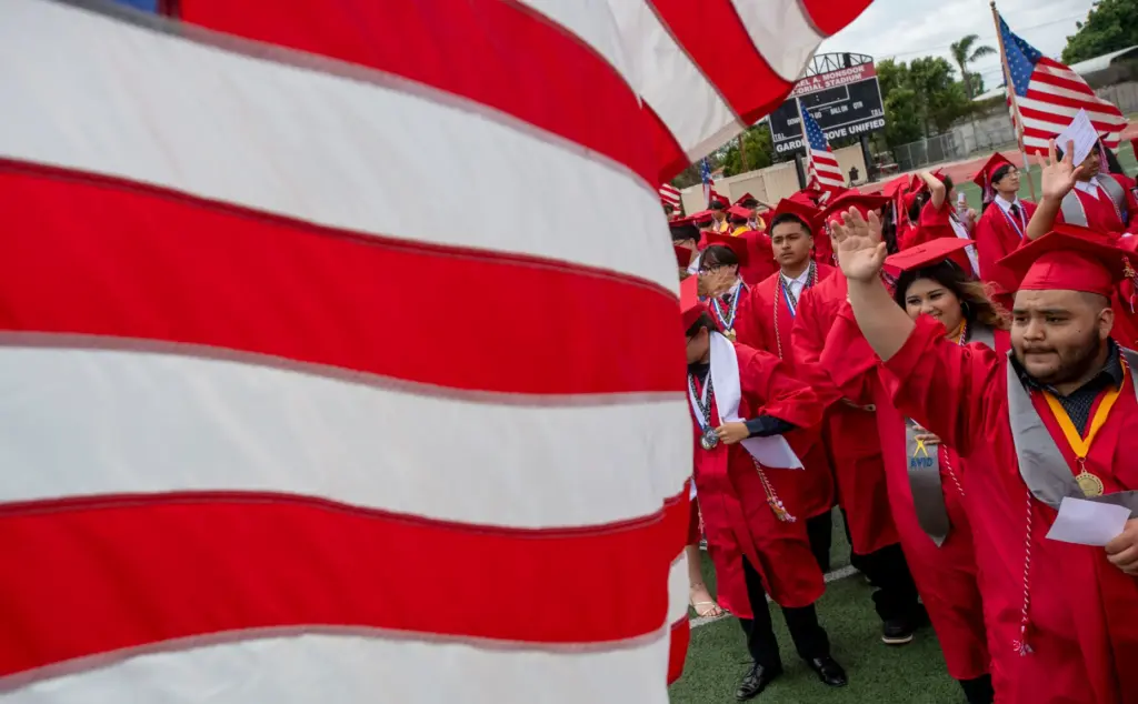 Graduates waves to the crowd as the march into the...