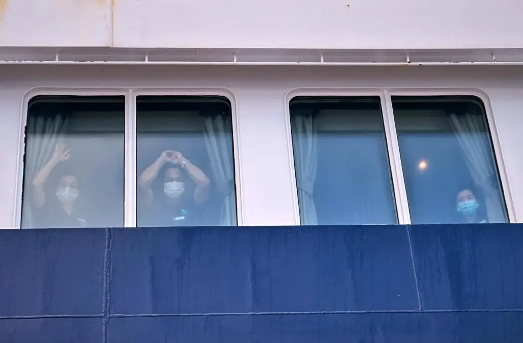 Passengers watch as others are disembarked from the hantavirus-stricken cruise...