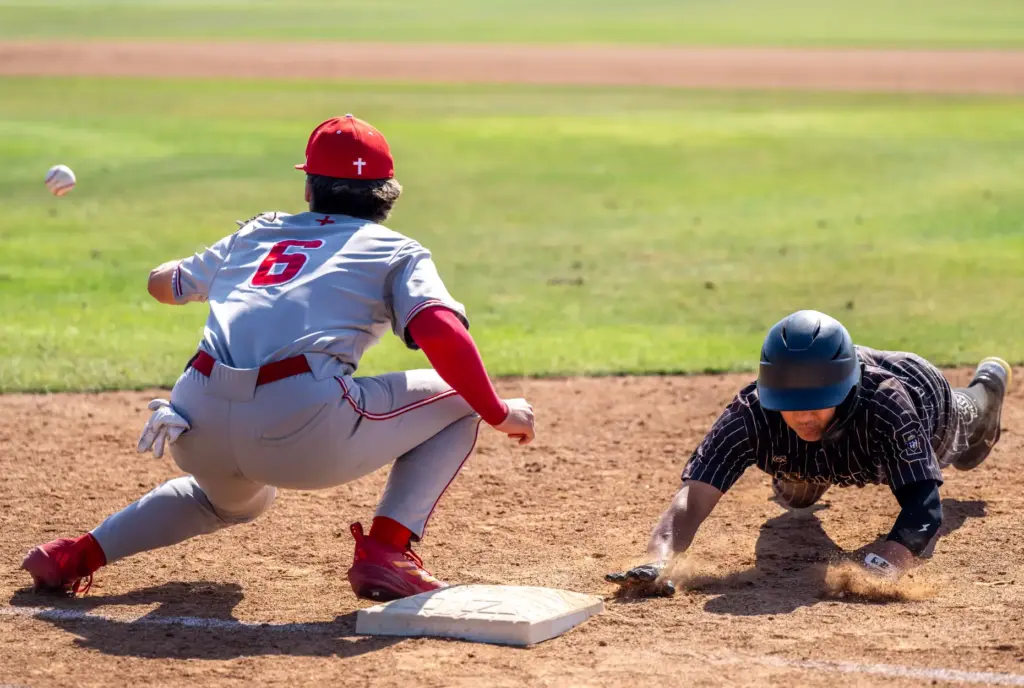 Serviteâs Lucas Alfaro-Chuan dives safely back to first base, avoiding...