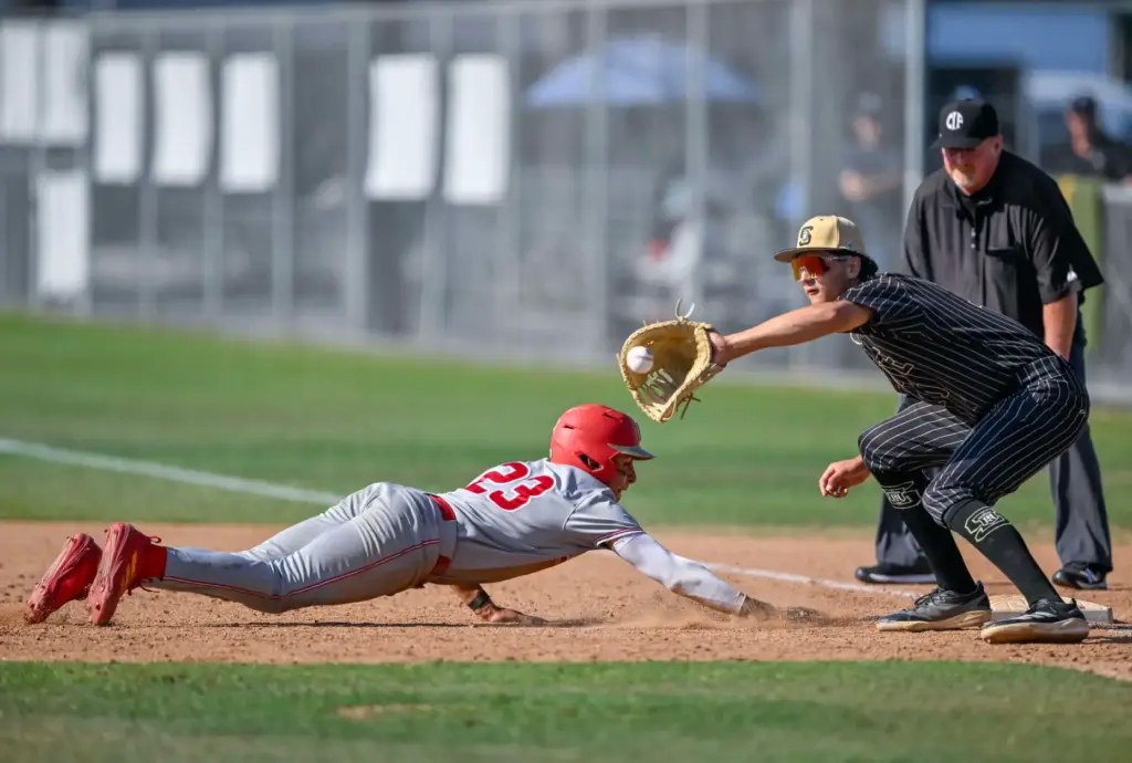 Orange Lutheran outfielder Ricardo Hurtado dives safely back to first...
