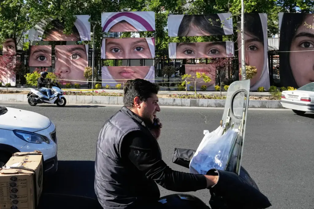 Vehicles drive past banners showing portraits of the school children...