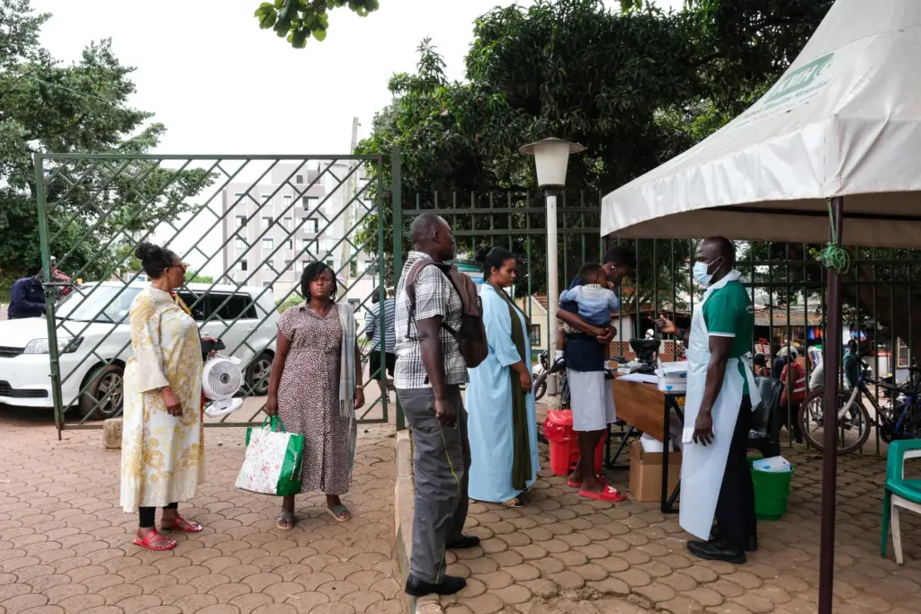 People wait to have their temperature taken in front of...