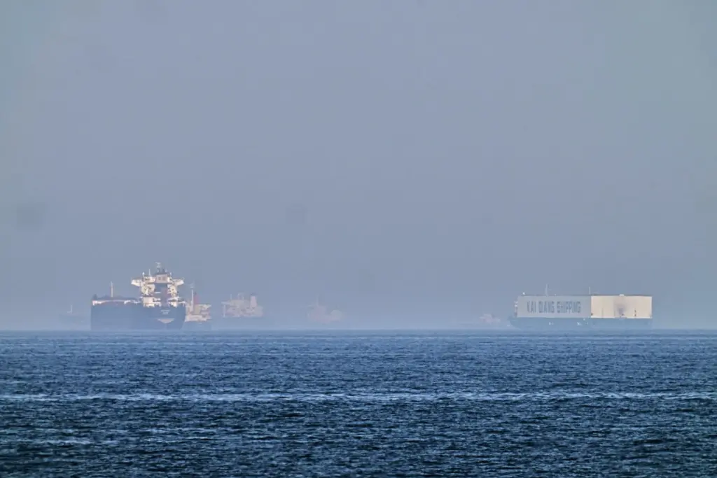 A tanker and a car carrier are anchored at sea in the Gulf of Oman.