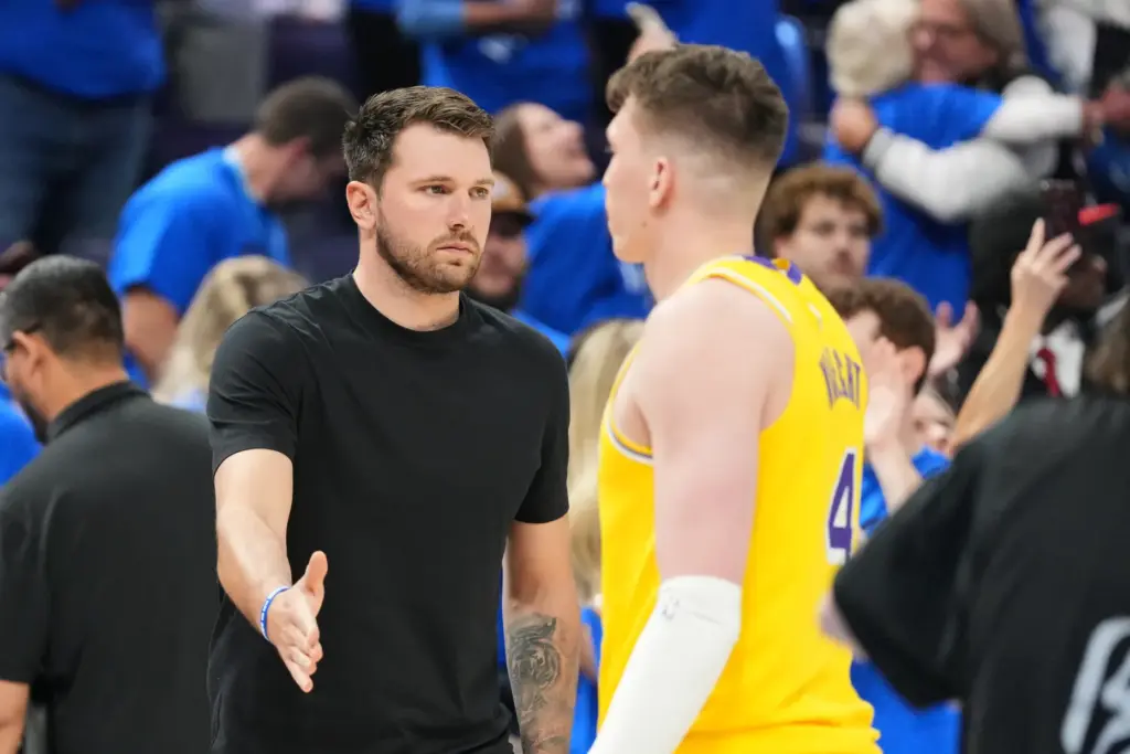 Injured Lakers star Luka Doncic, left, greets teammate Dalton Knecht,...