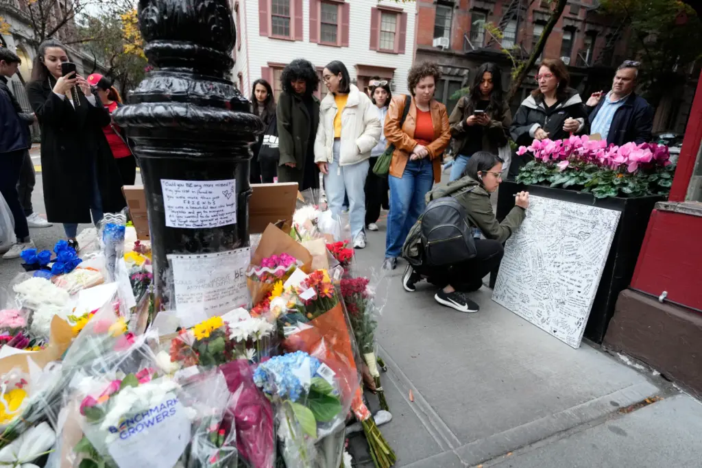 People gather by a makeshift memorial for Matthew Perry outside...