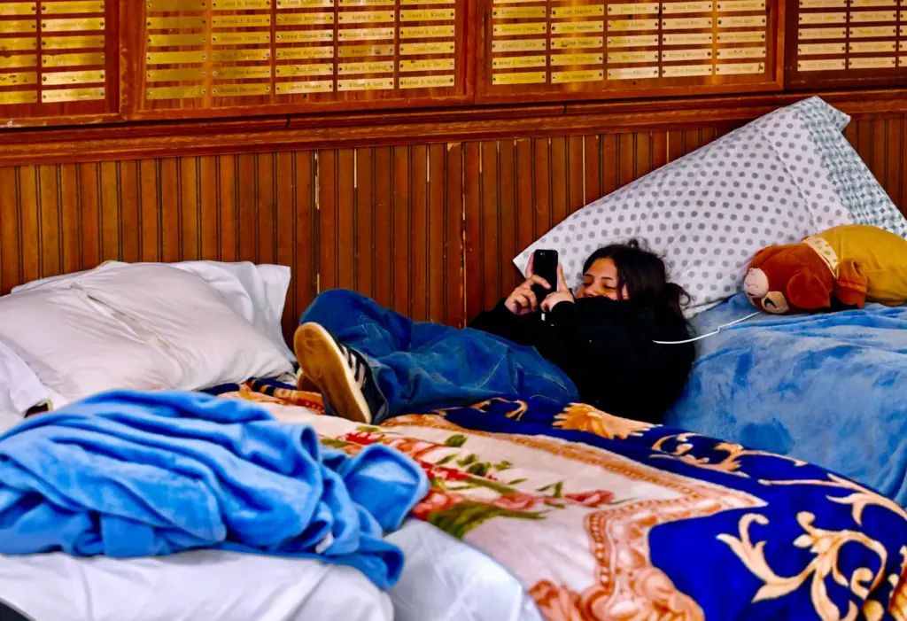 Evacuees Kylie Romero hangs out on a cot next to...