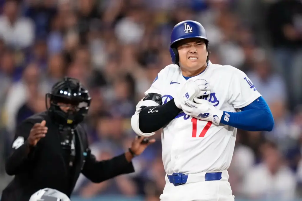 Dodgers star Shohei Ohtani reacts after being hit by a...