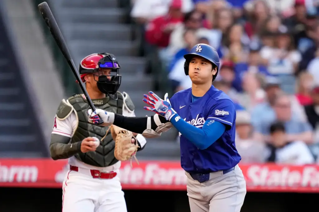 Dodgers star Shohei Ohtani, left, walks away after striking out...