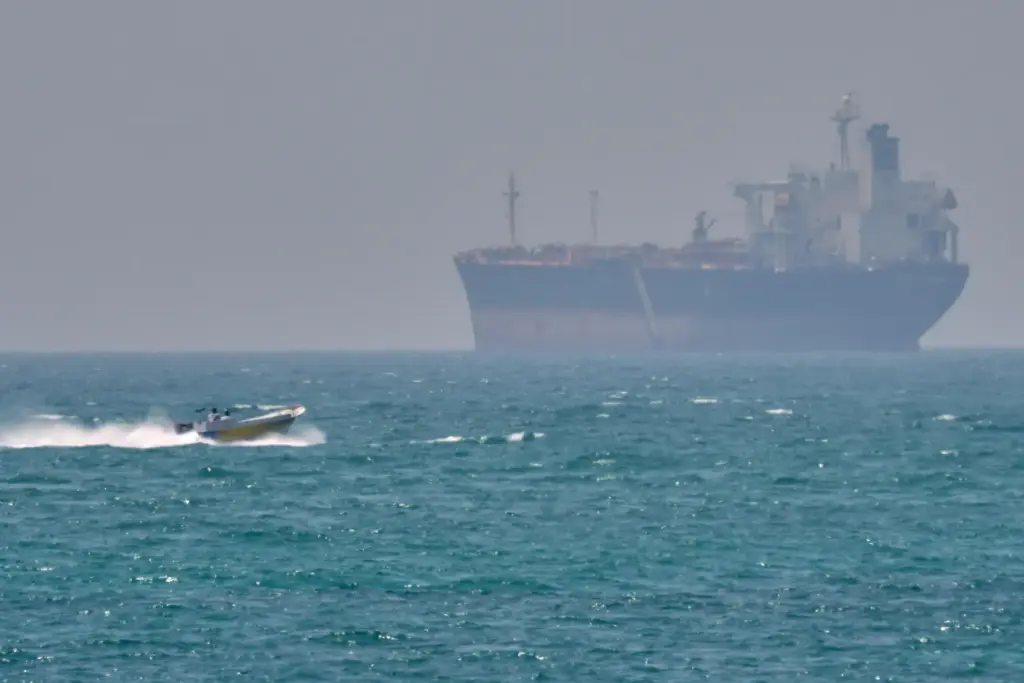 FILE – A boat sails past a tanker anchored on...