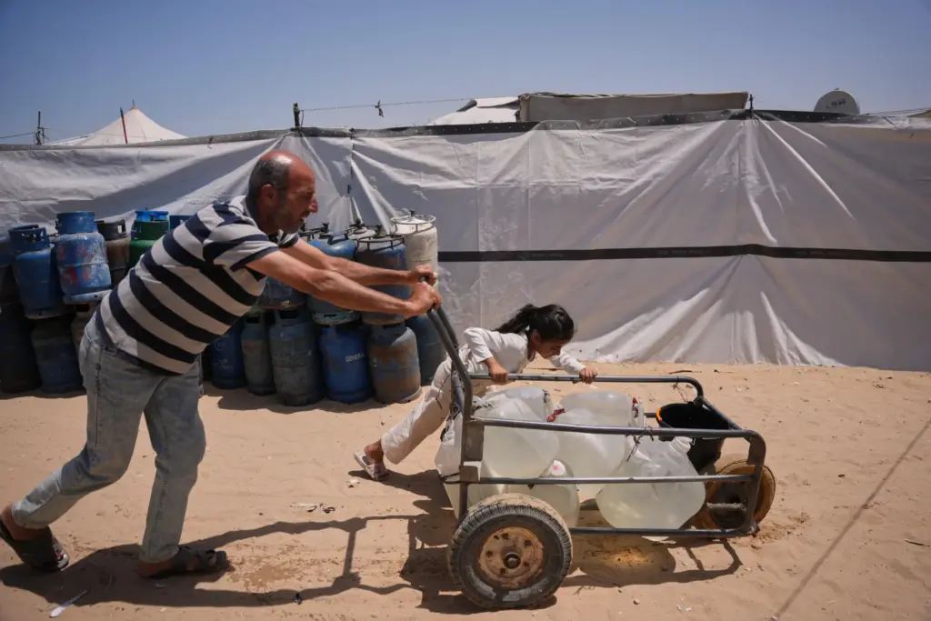 Ne'man Abu Jarad and his daughter push a cart loaded with jerrycans filled with water