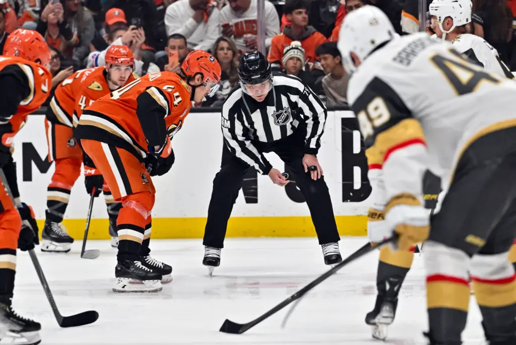 The referee prepares to drop the puck as the Ducks...