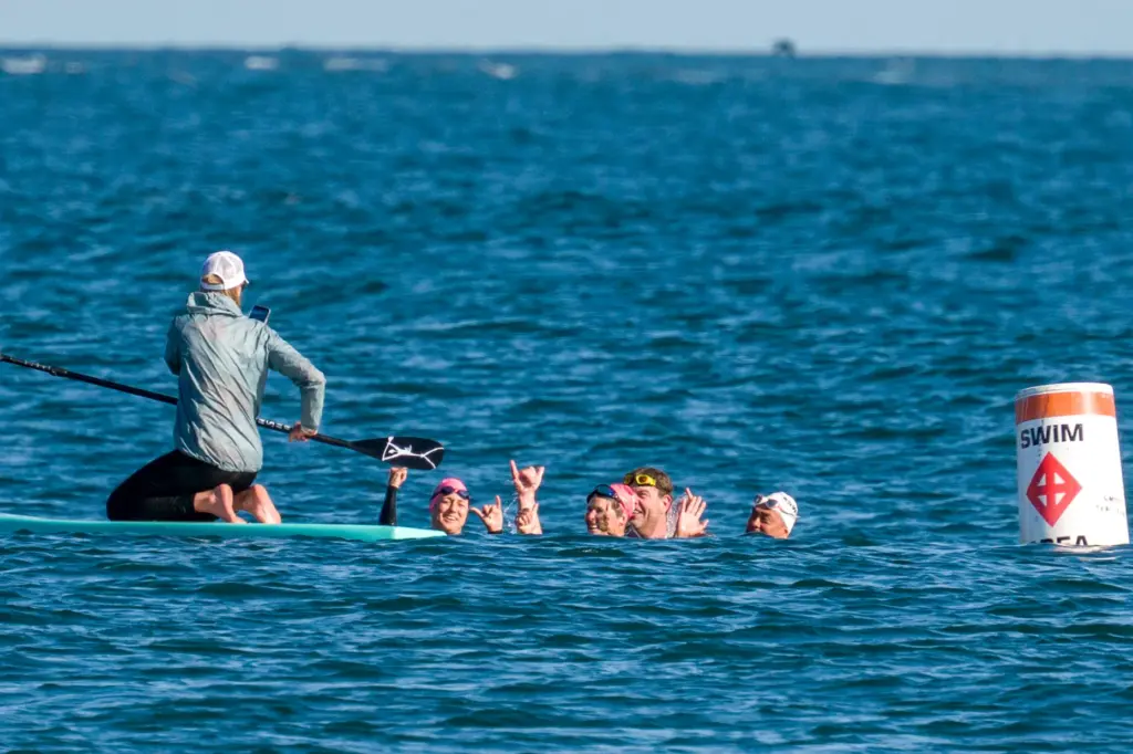Kristiina Beary, on surfboard, takes a photo of swimmers, from...