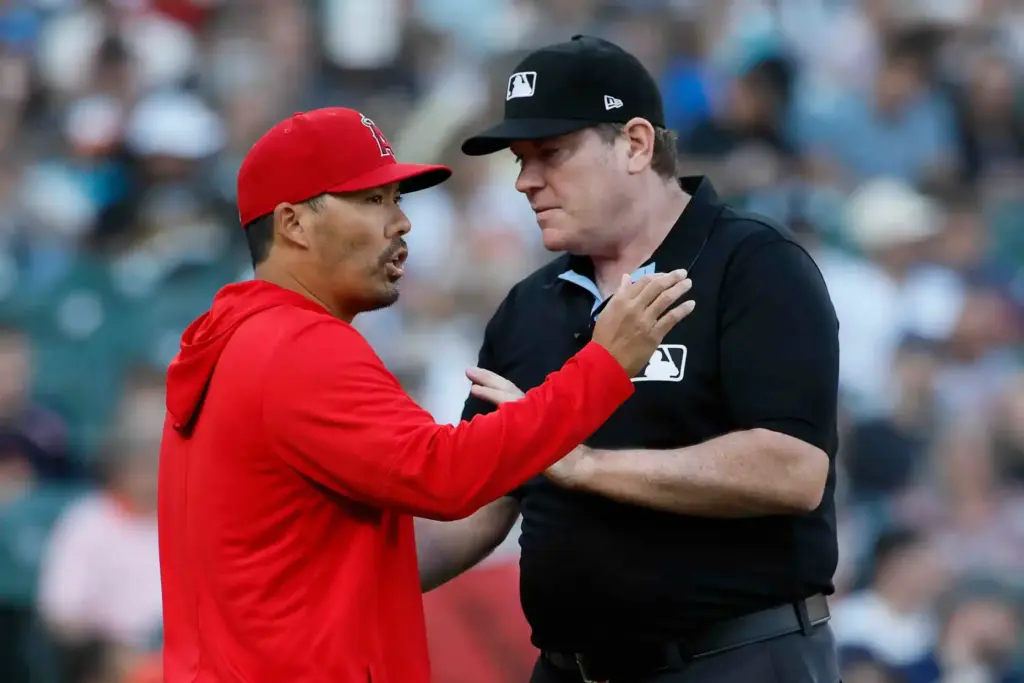 Angels manager Kurt Suzuki, left, argues with umpire Chris Conroy...