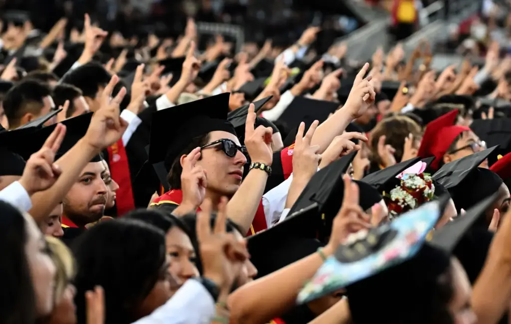 Graduates give the victory sign during USC’s 143rd commencement ceremony...