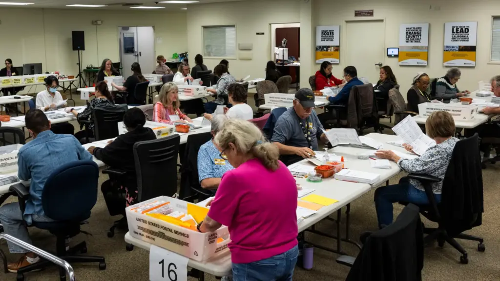Workers take in ballots in the vote-by-mail processing area at...