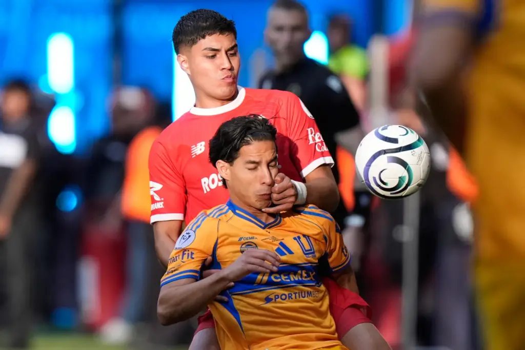 Toluca’s Everardo Lopez, top, and Tigres’ Diego Lainez vie for...
