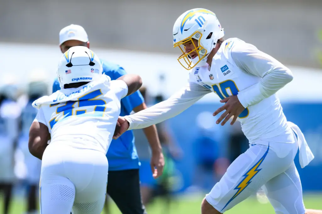 Chargers quarterback Justin Herbert, right, hands the ball off during...