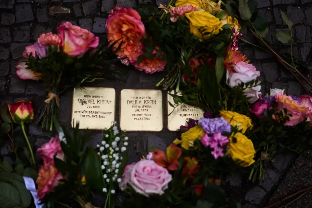 Flowers lay near palm-sized brass Holocaust plaque