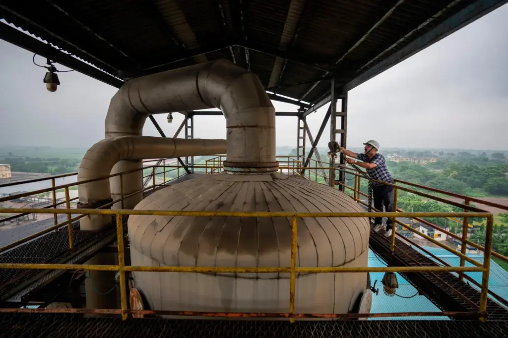 A technician works on the top deck of a distillery at Bajaj Hindustan Sugar factory.