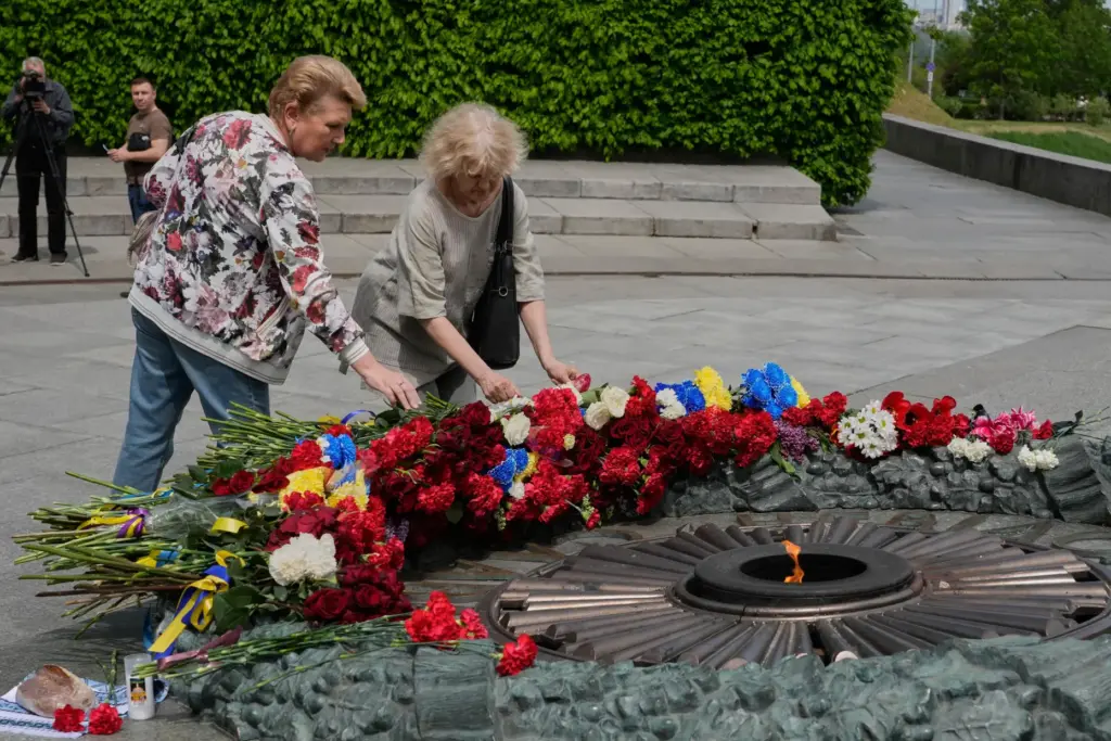 People lay flowers to the monument of the Unknown Soldier to mark Victory Day in Kyiv.