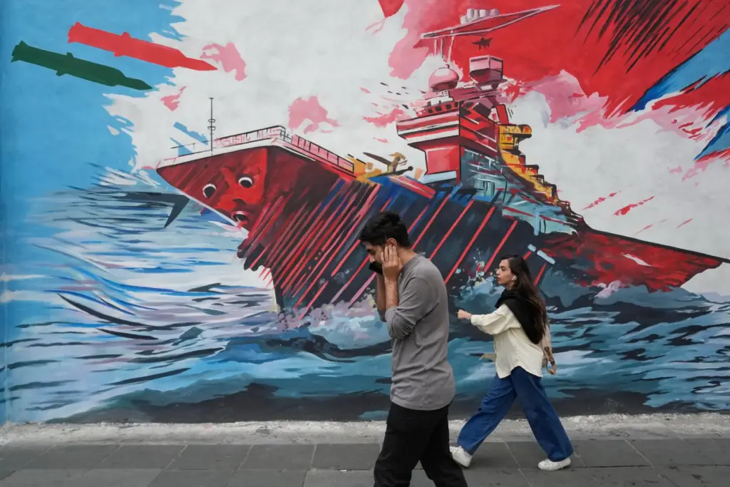 People walk past a mural depicting a U.S. aircraft carrier...