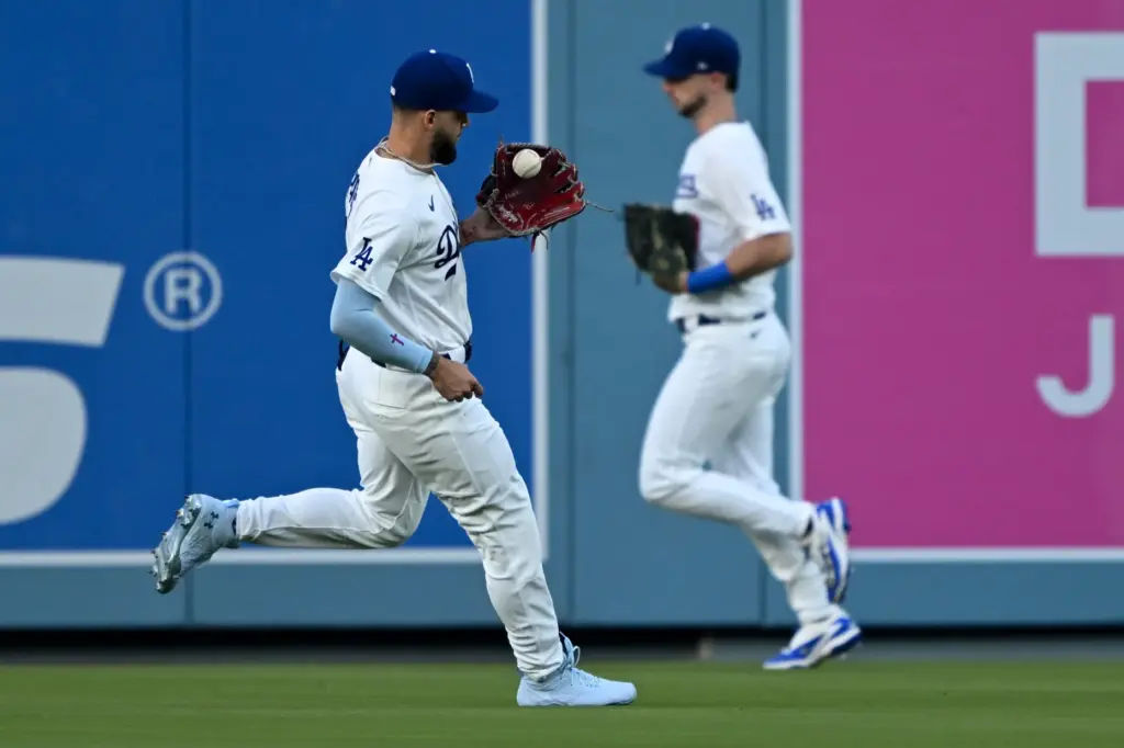 Dodgers center fielder Andy Pages, left, catches a fly ball...