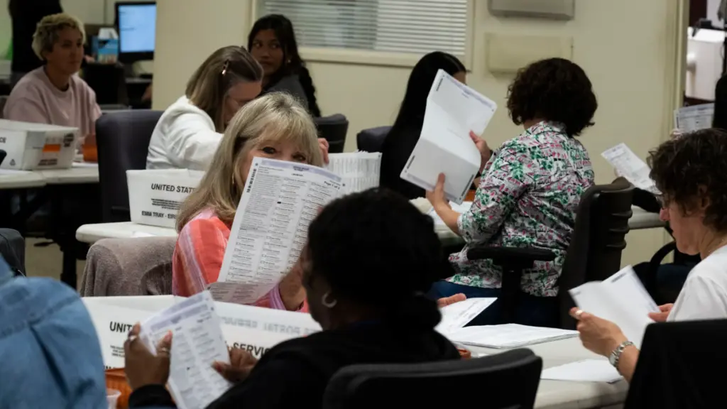Workers take in ballots in the vote-by-mail processing area at...
