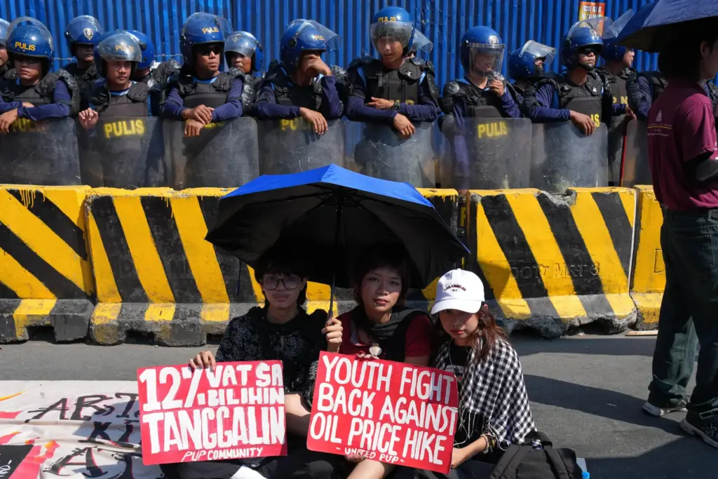 Protesters hold slogans beside police during a rally by transport workers and activists protesting the rise in oil prices