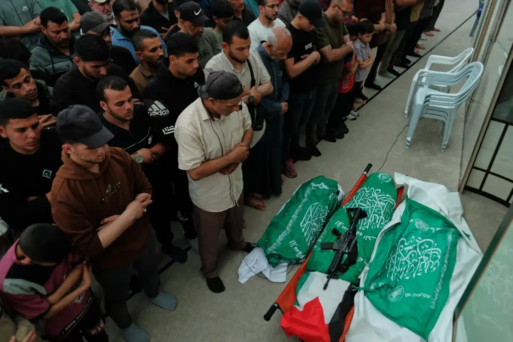 Palestinians pray over the bodies