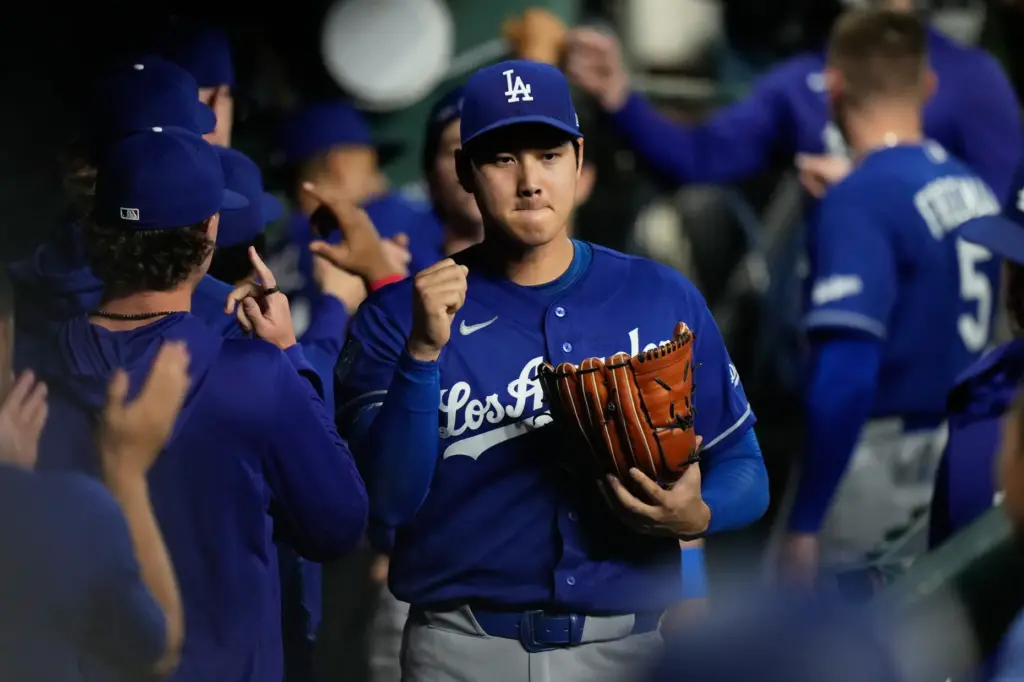 Dodgers starting pitcher Shohei Ohtani arrives in the dugout after...