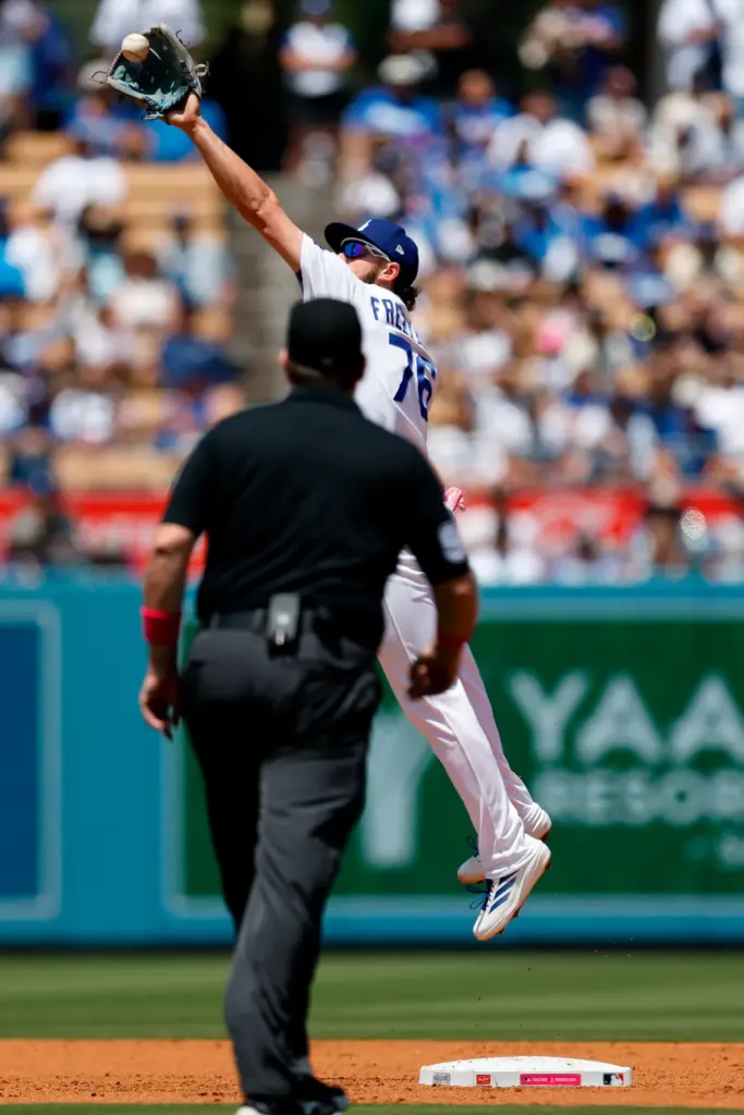 Dodgers second baseman Alex Freeland, top, jumps up to catch...