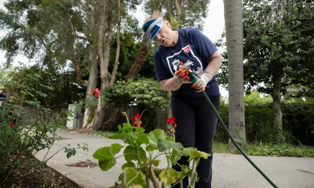 Barbara Mauger checks the hose before watering the garden at...
