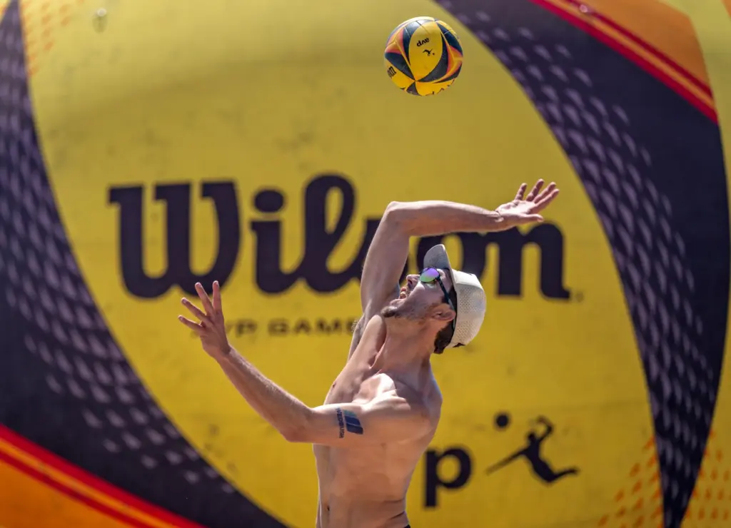 Miles Evans serves the ball, while playing with teammate Chase...