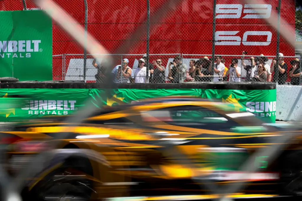 Spectators peer through the fence for the IMSA WeatherTech SportsCar...