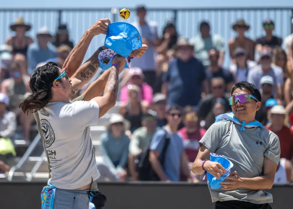 Audience participants compete to catch miniature volleyballs in hats during...