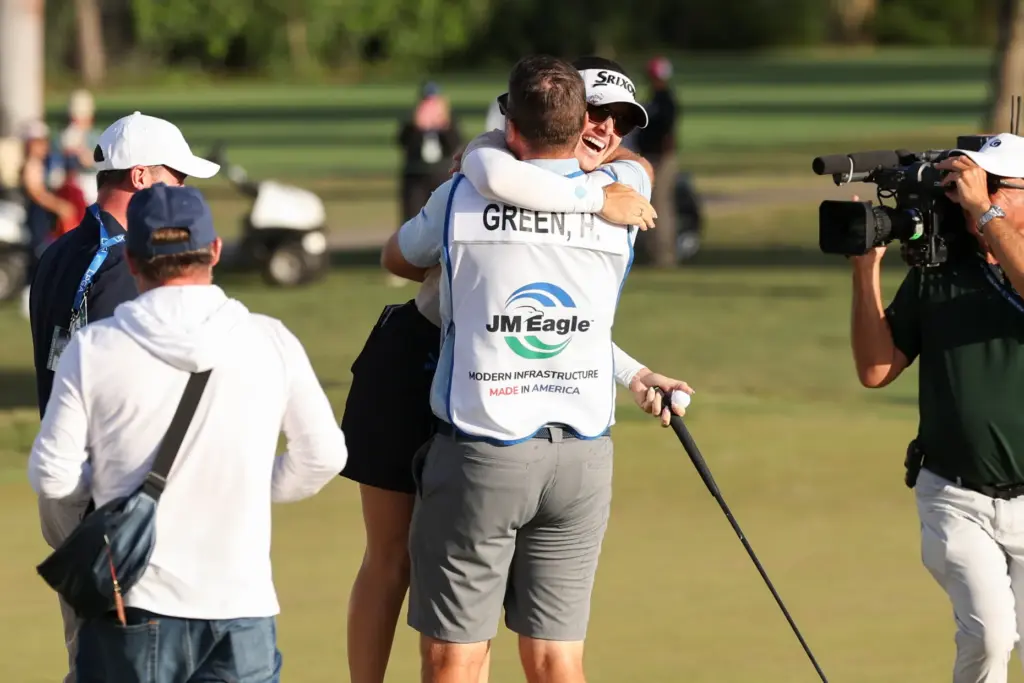 Hannah Green, back center, and her caddie David Buhai, front...