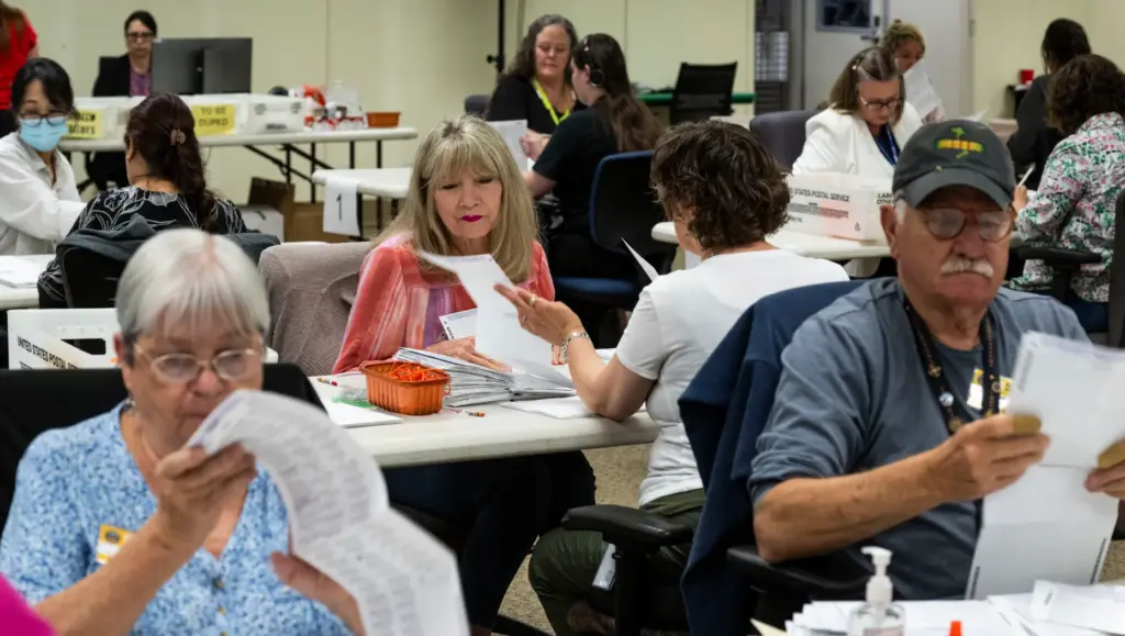 Workers take in ballots in the vote-by-mail processing area at...