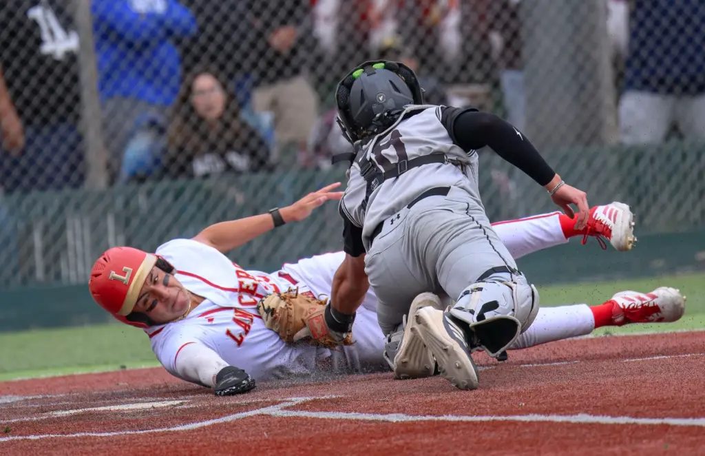 Orange Lutheran’s Ricardo Hurtado is tagged out by Santiago catcher...