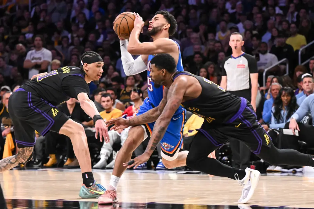 The Oklahoma City Thunder’s Ajay Mitchell drives between Lakers guard...