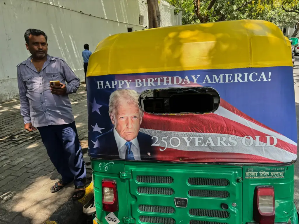 Pradeep Kumar stands next to his auto-rickshaw featuring a poster of President Donald Trump.