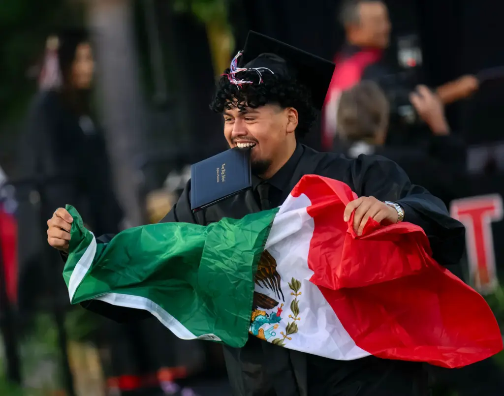 A graduate celebrates after receiving his diploma at the Troy...