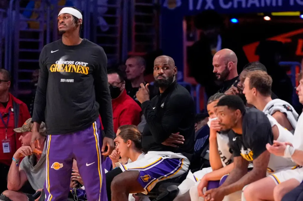 Lakers forward LeBron James, center, watches from the bench as...